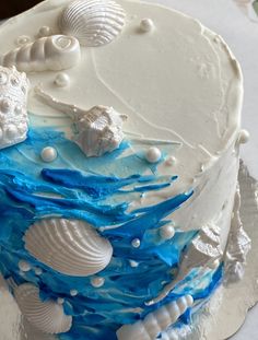 there is a blue and white cake with shells on the top, along with other decorations