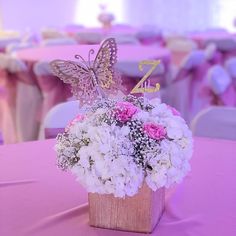 a vase filled with white and pink flowers on top of a purple table cloth covered table