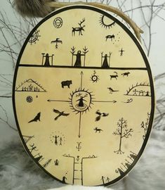 a wooden clock with animals and trees on it's face in front of some branches