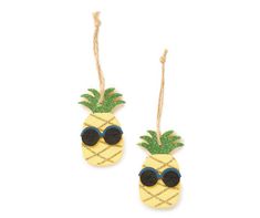 two pineapples with sunglasses hanging from strings