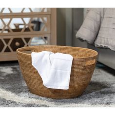 a basket with a white towel in it sitting on the floor next to a bed