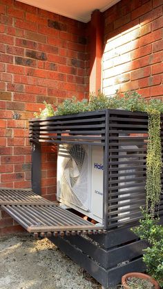 an air conditioner sitting on top of a wooden bench next to a brick wall