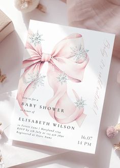 a baby shower card with a pink bow and snowflakes on it, surrounded by flowers