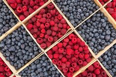 raspberries and blueberries are arranged in boxes