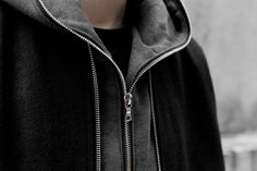 black and white photograph of a person wearing a hoodie with zippers on it