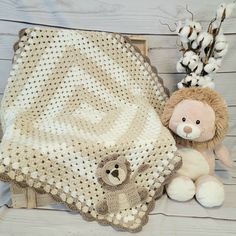 a crocheted blanket and teddy bear next to cotton flowers