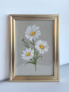 a painting of white daisies in a gold frame