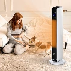 a woman sitting on the floor next to an air purifier and a dog