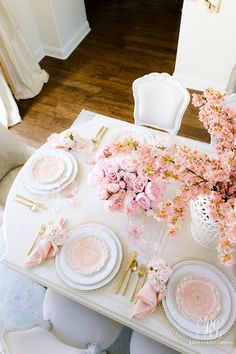 the table is set with pink flowers and place settings