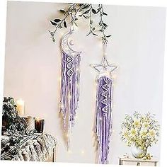 two purple and white dream catchers hanging on the wall next to a plant in a vase