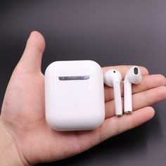 a person holding an apple airpods in their left hand and two ear buds attached to it