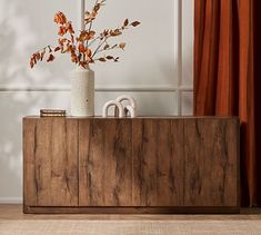 a vase filled with flowers sitting on top of a wooden cabinet