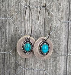 pair of earrings with turquoise stone in center on wooden fence post, close - up