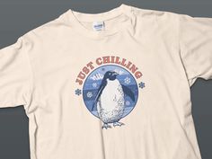 Embrace the cool vibes with this adorable "Just Chilling" penguin T-shirt. Featuring a charming penguin graphic against a snowy mountain backdrop, surrounded by gently falling snowflakes, this tee is perfect for winter enthusiasts or anyone who loves cute animal designs. Made with high-quality material, it's comfortable for everyday wear and sure to be a hit at any casual gathering. Product Features: Model: Gildan 5000, Unisex Heavy Cotton Tee Medium-weight cotton fabric 5.3 oz/yd² (180 g/m²) fo Short Sleeve Graphic T-shirt For Winter, Winter Graphic Print Short Sleeve T-shirt, Winter Graphic Print T-shirt With Short Sleeves, Penguin Graphic, Mountain Backdrop, Penguin T Shirt, Cool Vibes, Mountain Tshirt, Snowy Mountain