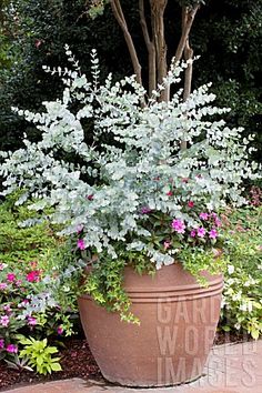 a large potted planter filled with white and pink flowers on top of a brick walkway