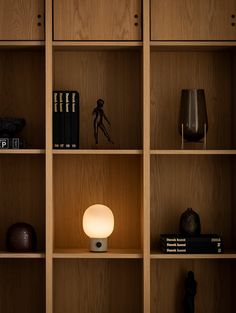 a wooden shelf with books and other items on it, along with a small lamp