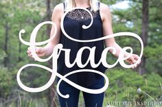 a woman standing in the woods holding her hands out with the word grace written on it