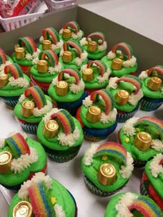 there are many cupcakes with green frosting and gold decorations on them in a box