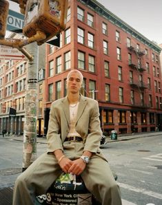 a man sitting on top of a pole next to a traffic light in the city