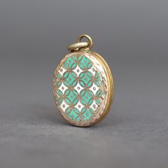 An eye-catching antique enamel locket in 9ct yellow gold (back and front), most likely dating to the late-Victorian era (1837-1901). The front of the locket is adorned with seafoam green enamel in a geometric pattern, while the back is engraved with ivy, symbolic of loyalty and devotion. The fittings and jump ring are base metal (probably brass). No stamps are present but the gold tests as a minimum of 9ct. Weight (approximate): 5.8g Measurements (approximate): 25mm x 20mm (not including bale). Condition: Good, with wear commensurate with age. There are minor losses to the enamel. The gold and metal have light marks and general wear. There are a few small solder marks to the metal frame. Please see pictures for details and don't hesitate to ask questions. Please note: the necklace shown in Oval Enamel Locket Jewelry, Vintage Enamel Oval Pendant Jewelry, Antique Enamel Locket Jewelry, Victorian Green Medallion Jewelry, Green Locket Jewelry, Green Medallion Locket Jewelry, Antique Green Locket Jewelry, Enamel Locket, Antique Locket