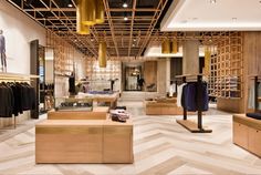 the inside of a clothing store with wooden shelves and clothes hanging on racks in it