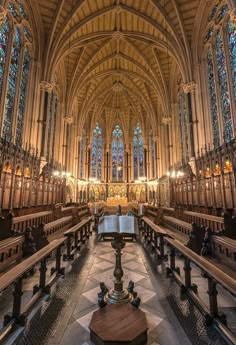 the interior of a cathedral with pews and stained glass windows on both sides,