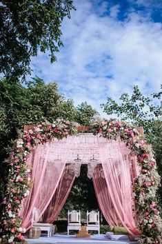 an outdoor wedding ceremony with pink drapes and flowers on the arch over the aisle