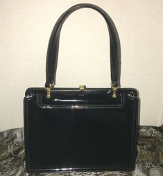 Vintage Mam’Selle NY Black Patent Handbag Red Interior. Elegant Mam’Selle Originals, NY shiny black patent leather block purse. It has red leather interior, brass hardware, double leather straps and bottom studs. It has a zippered pocket and three sleeve pockets. It measures approximately 7.5” H x 9.5” W x 4” D and a 6.5” strap drop. The inside corners have some splits from opening and closing purse and some scratches on outside that’s typical with age. See photos as they are part of description