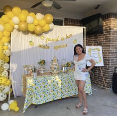 a woman standing in front of a table with yellow and white balloons