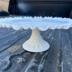 a white cake plate sitting on top of a wooden table