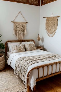 a bed with white sheets and pillows in a bedroom next to a potted plant