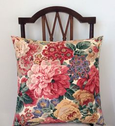 a floral pillow sitting on top of a wooden chair