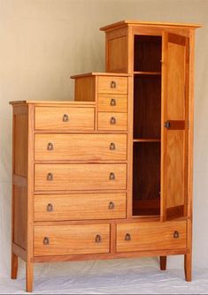 a wooden dresser with many drawers and doors on it's sides, in front of a white wall