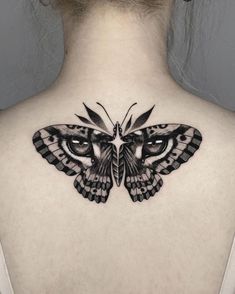 a woman's back neck with a butterfly tattoo on the upper part of her body