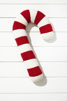 a red and white striped candy cane on top of a white wall with wood planks