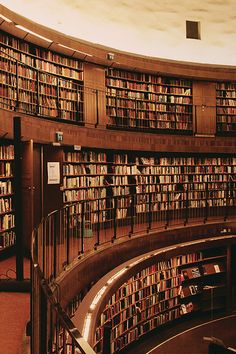 the inside of a library with many books on shelves and stairs leading up to them