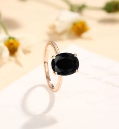 a black diamond ring sitting on top of a piece of paper with flowers in the background