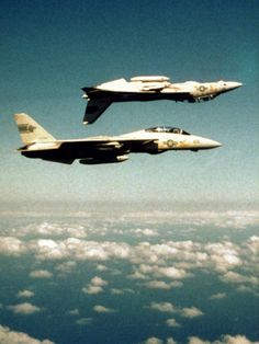 two fighter jets flying in the sky above clouds