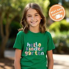 Welcome your little one to a new adventure with the Hello Kindergarten School Shirt. These unisex kindergarten shirts are perfect for the First Day of School, offering a fun and stylish way to celebrate this big milestone. Whether for preschool or kindergarten, this Back to School Shirt is designed to make them feel excited and confident. Ideal as a Kids Gift, this shirt is a wonderful way to mark the start of their educational journey. ✨ F E A T U R E S ✨ 👕 Tailored fit with vibrant colors tha Playful Funny Print T-shirt For School, Green Letter Print T-shirt For Playtime, Playful T-shirt For Back To School, Playful Tops For End Of School Year Playtime, Cotton T-shirt For End Of School Year Playtime, Back To School T-shirt With Name Print For Daycare, Name Print T-shirt For Daycare And Back To School, End Of School Year Playtime Cotton T-shirt, Fun Green T-shirt For School