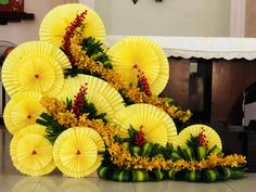 several yellow paper umbrellas are arranged on the floor in front of flowers and greenery