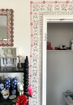 a shelf with vases, plates and other items on it next to a mirror