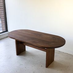 a wooden table sitting in front of a window next to a white wall and floor