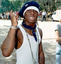 a man wearing a hat and bandana making the peace sign with his hand while standing in front of a group of people