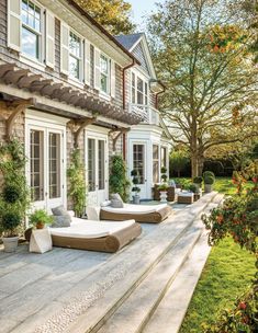 an outdoor patio with chaise lounges and potted plants on the side of it