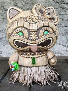 a wooden cat statue sitting on top of a table next to a stone wall with green eyes