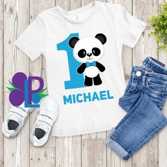 a t - shirt with a panda bear on it next to some baby shoes and a pair of jeans