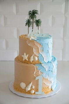 a three tiered cake decorated with palm trees and seashells on a white table