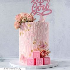 a pink cake decorated with flowers and the word baby spelled out in large letters on top