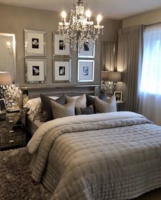 a bedroom with a large bed, chandelier and pictures on the wall above it