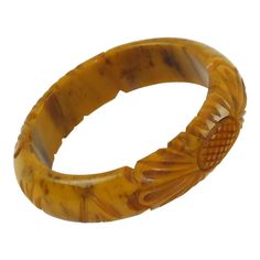 This is part of Chairish’s Costume Jewelry assortment.  This stunning banana brown marble Bakelite carved bracelet bangle features a domed shape with deep floral carving, two designs on the bracelet, and a thick wall. The piece boasts an intense caramel yellow marbled tone with cloudy brown swirls, also called banana brown color. Measurements: Inside across is 2.57 in diameter (6.5 cm) - outside across is 3.32 in diameter (8.4 cm) - width is 0.75 in wide (1.9 cm) - wall is 0.38 in thick (1 cm). Antique Brown Carved Jewelry, Brown Bakelite Bangle Bracelet, Brown Carved Bangle Bracelets, Vintage Carved Brown Bracelets, Vintage Brown Carved Bracelets, Brown Carved Bracelet Jewelry, Luxury Carved Bangle Bracelets, Luxury Carved Bangle Bracelet, Carved Brown Bangle Jewelry